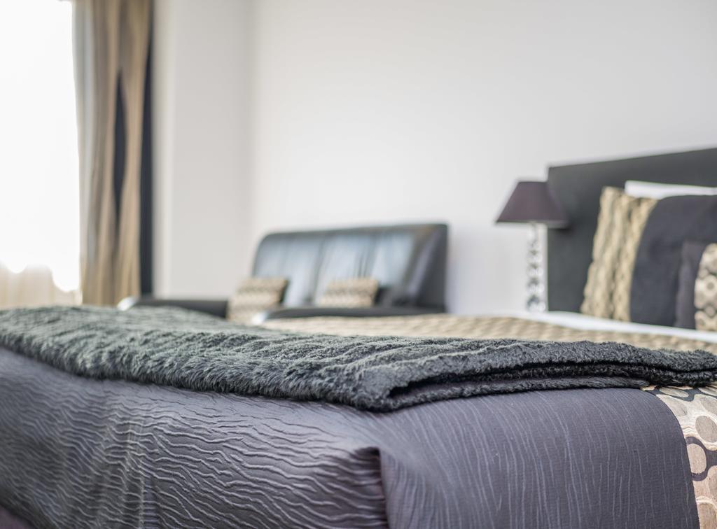 Bellano Motel Suites Christchurch Bagian luar foto A bed with a throw
